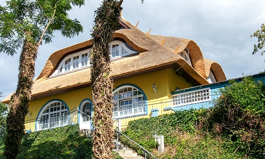 Gästehaus Bergfalke, Abendbeleuchtung, Treppe vor dem gelben Haus mit Reetdach