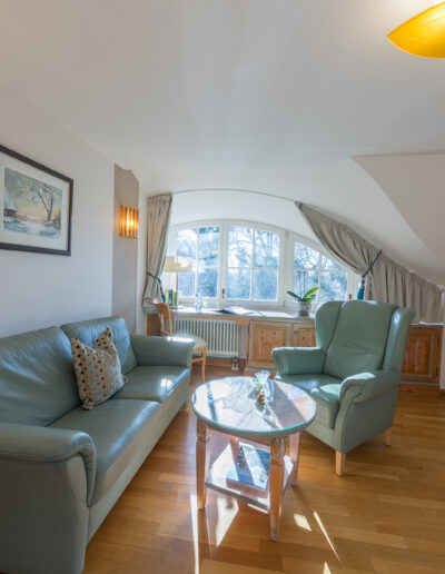 Juniorsuite Deluxe, Wohnzimmer mit großem Rundbogenfenster und grüner Leder-Sitzgarnitur