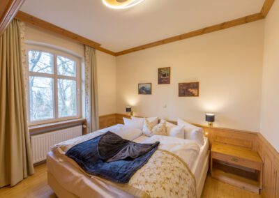 Schlafzimmer mit Doppelbett, Nachttischen mit Lampen und Fenster mit Blick ins Grüne; Gästezimmer in der Alten Malschule