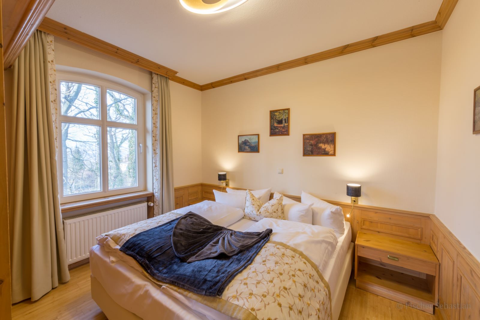 Schlafbereich, Gästezimmer in der Alten Malschule Schlafzimmer mit Doppelbett, Nachttischen mit Lampen und Fenster mit Blick ins Grüne; Gästezimmer in der Alten Malschule